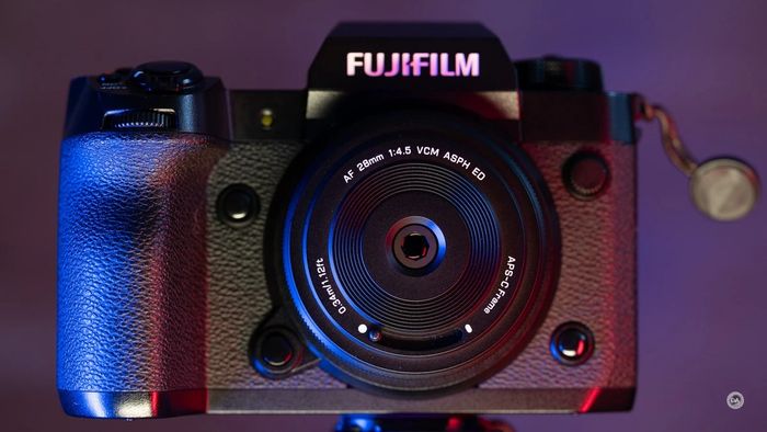 Фронтальний вигляд бездзеркальної камери Fujifilm з надтонким Viltrox AF 28mm f/4.5 Chip у студійному синьо-червоному підсвічуванні, важіль металевої шторки закриває вхідну лінзу замість кришки